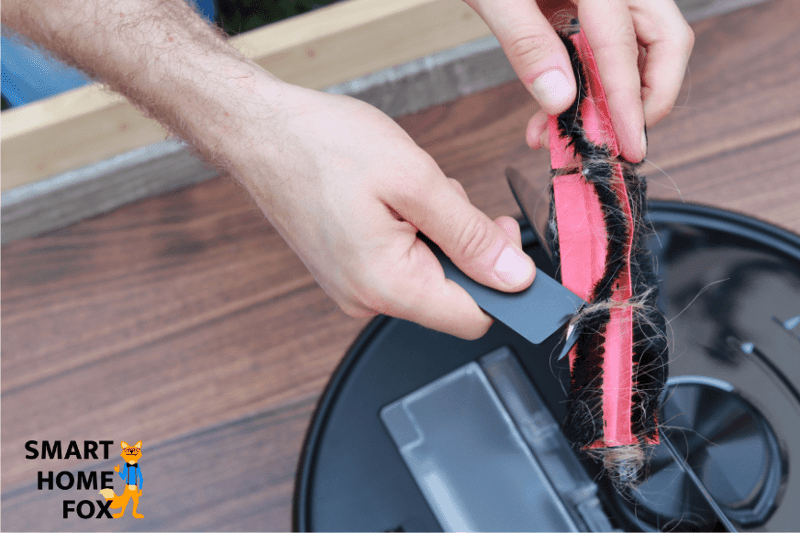 Haare werden mit Hilfe des mitgelieferten Reinigungswerkzeugs aus der Bürste des Roborock S6 MaxV entfernt